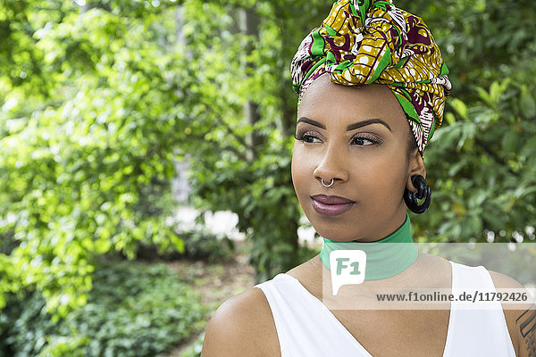 Porträt einer jungen Frau mit Piercings in traditioneller brasilianischer Kopfbedeckung