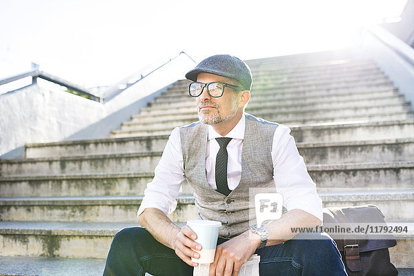 Geschäftsmann mit Kaffee und Zeitung in der Stadt auf der Treppe sitzend
