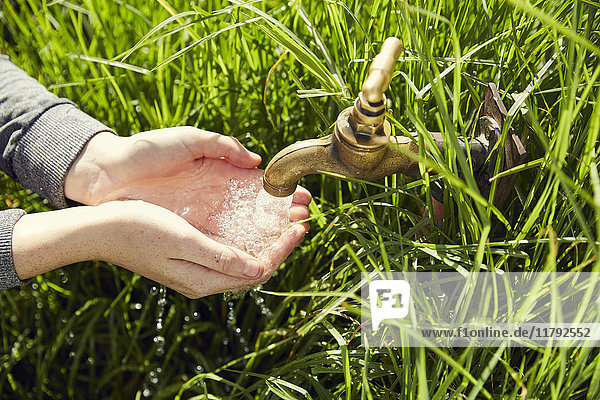 Hände einer jungen Frau trinken Wasser aus einem Brunnen  Nahaufnahme