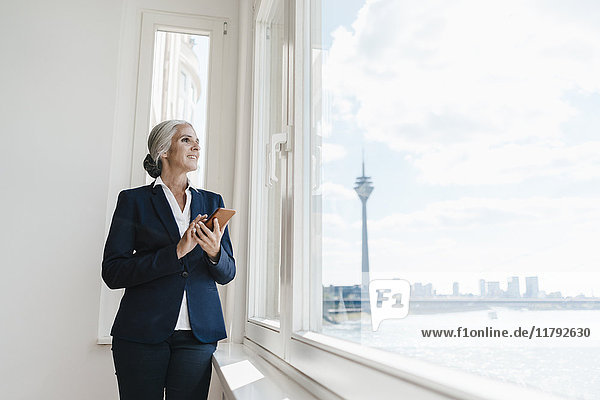 Businesswoman looking out of window in waterfront office
