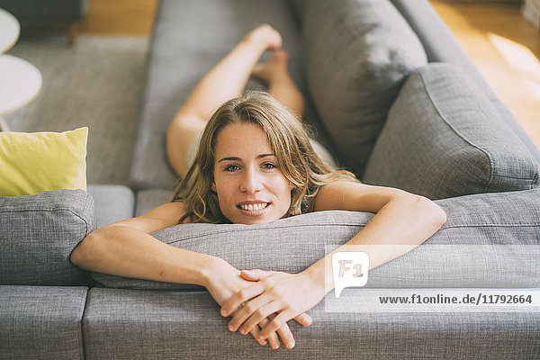 Porträt einer jungen Frau  die sich zu Hause auf der Couch entspannt.