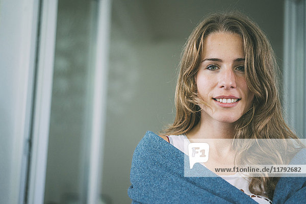 Porträt einer lächelnden jungen Frau in eine Decke gehüllt