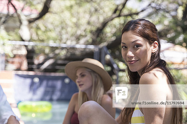 Portrait of smiling young woman in garden at the poolside