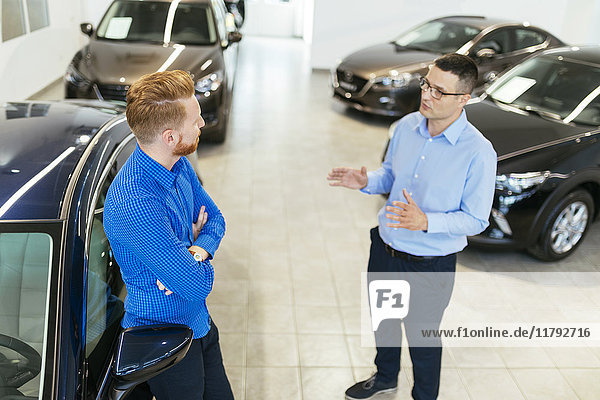 Salesman advising customer in car dealership