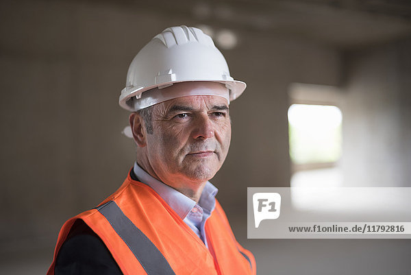 Portrait of man wearing safety vest in building under construction