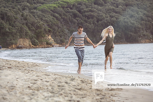 Glückliches Paar  das am Strand läuft