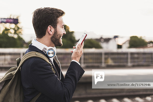 Smiling young man using cell phone on platform