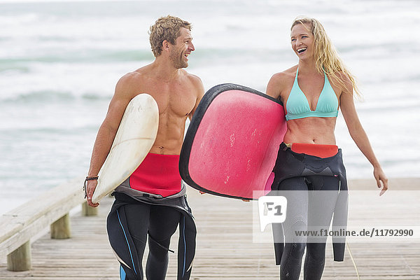 Couple walking from beach with surfboards