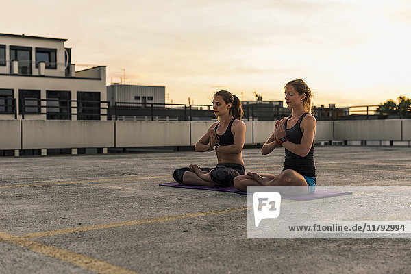 Zwei Frauen praktizieren Yoga auf Parkebene in der Stadt