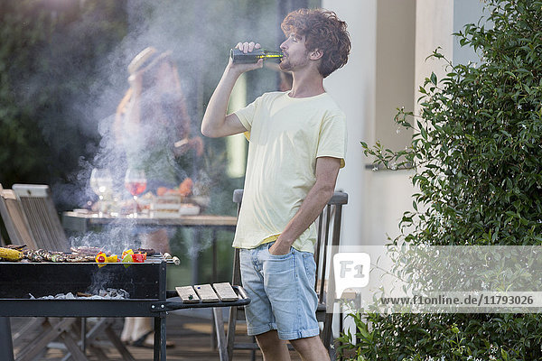 Man having a beer at barbecue grill