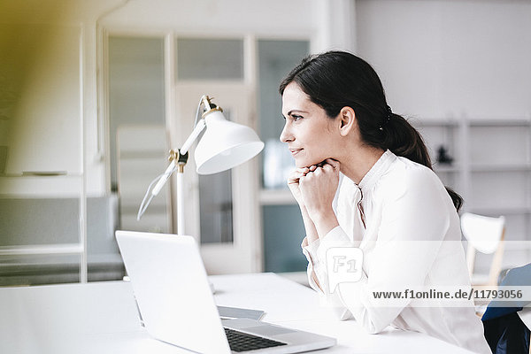 Businesswoman with laptop at table thinking