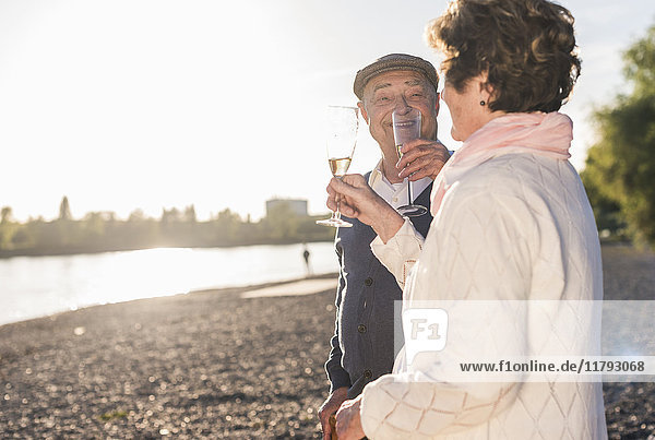 Seniorenpaar-Toasting mit Sekt bei Sonnenuntergang