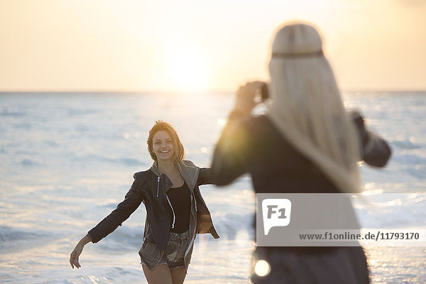 Friends taking pictures on the beach at sunset