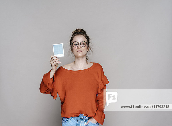 Portrait of young woman holding instant photo