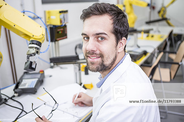 Portrait of smiling engineer in factory taking notes