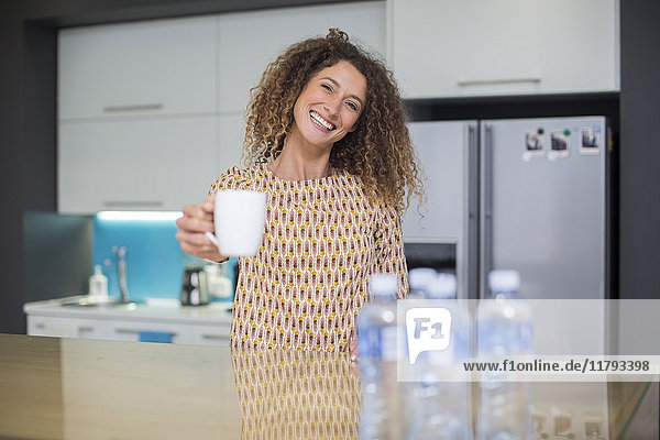 Porträt der lächelnden Frau in der Büroküche mit Tasse
