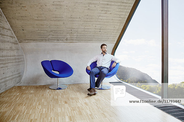 Geschäftsmann sitzend auf Stuhl im Dachbodenbüro