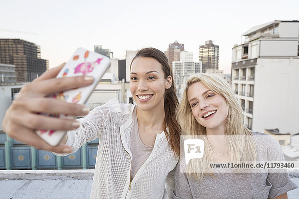 Friends taking selfies on a rooftop terrace