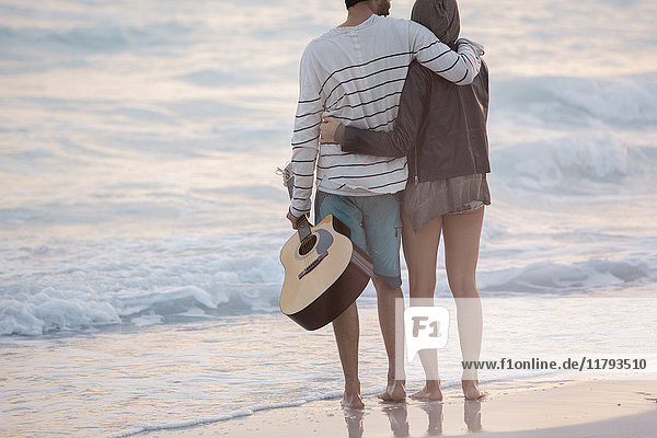 Young couple looking at the sea with arms around