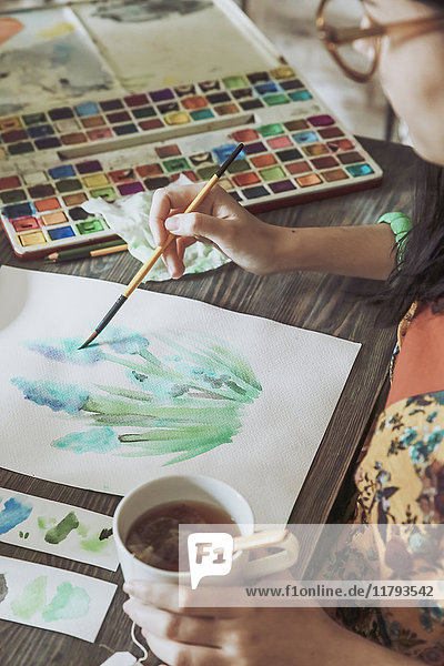 Young woman painting plants with water colors