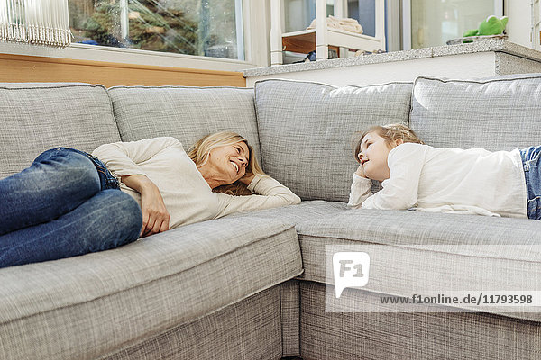 Reife Frau und Mädchen zu Hause auf der Couch liegend