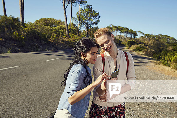 Südafrika  Kapstadt  Signal Hill  zwei lächelnde junge Frauen mit Handy auf Reisen
