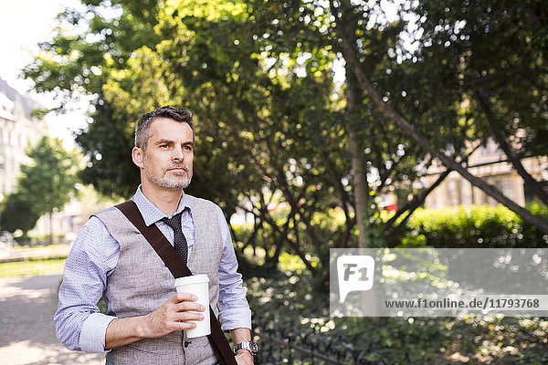 Erwachsener Geschäftsmann mit Kaffee im Stadtpark