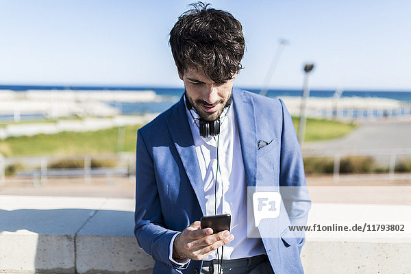 Young businessman looking at smartphone outdoors