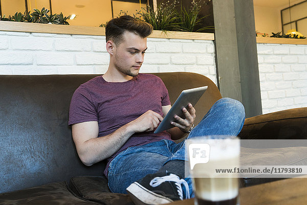 Junger Mann mit Tablette in einem Cafe
