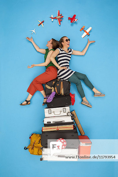Friends sitting on pile of luggage waiting for departure