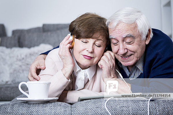 Seniorenpaar auf der Couch liegend  Musik hören vom digitalen Tablett