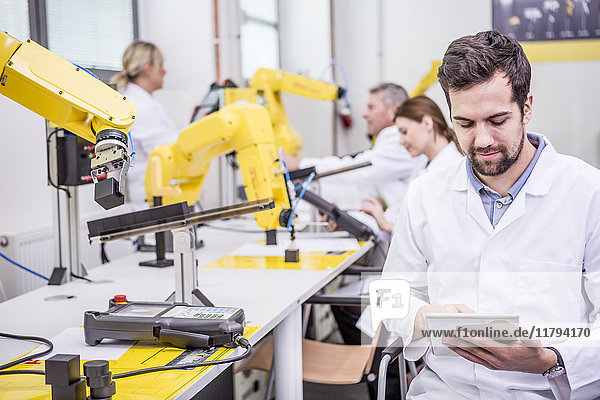 Ingenieur mit Tablette in der Fabrik mit Industrierobotern