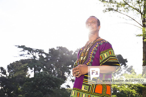 Portrait of smiling man standing at backlight wearing traditional Brazilian clothing