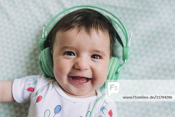 Portrait of laughing baby girl with headphones