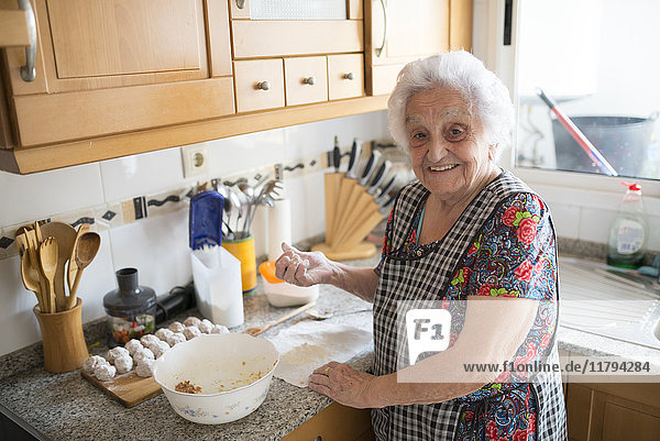 Porträt der lächelnden Seniorin bei der Zubereitung von Fleischbällchen in der Küche