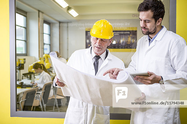 Two engineers in factory looking at plan