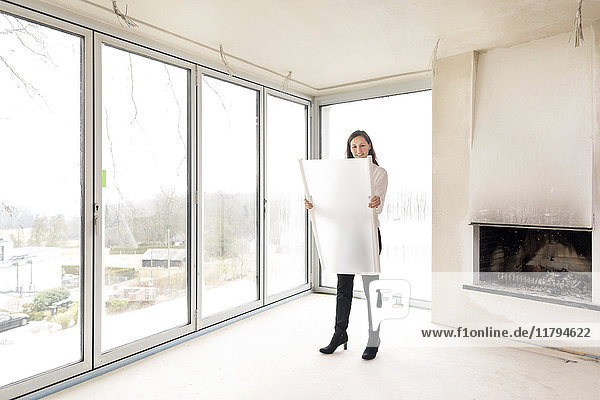 Woman in empty apartment with plan