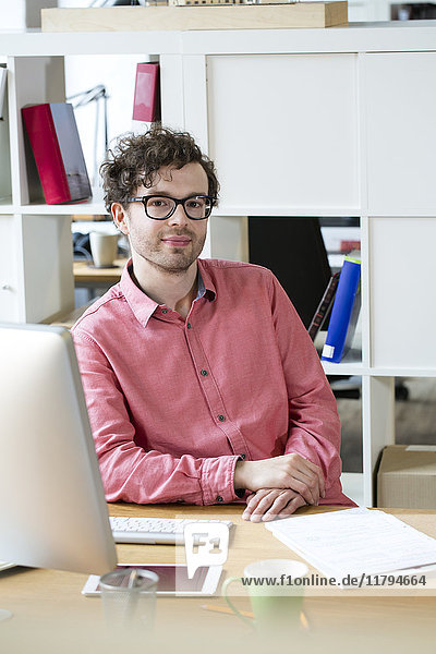 Porträt eines selbstbewussten Mannes am Schreibtisch im Büro