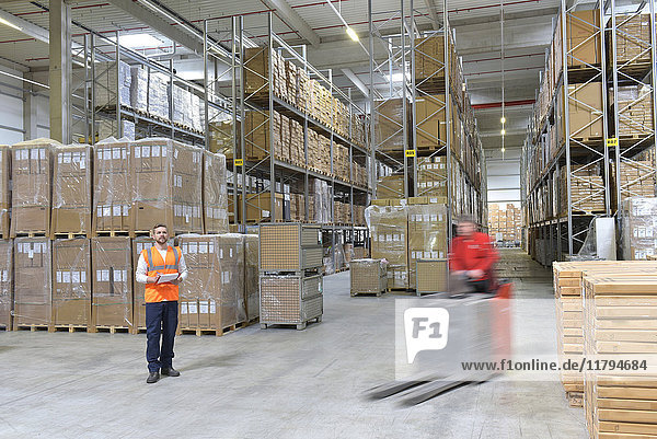 Man in factory hall and moving forklift