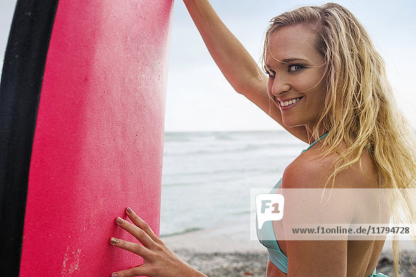 Smiling woman on beach with surfboard