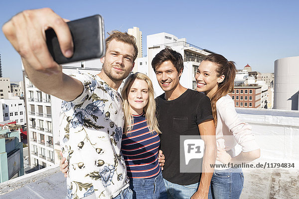 Friends taking selfies on a rooftop terrace