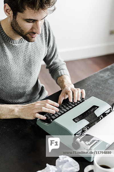 Young man at desk using typewriter