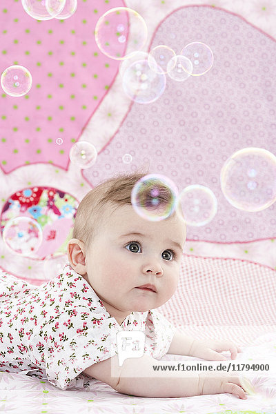 Porträt eines kleinen Mädchens  das Seifenblasen beobachtet.