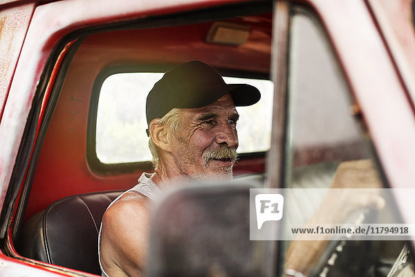 Ein älterer Mann  der einen alten Pick-Up fährt.