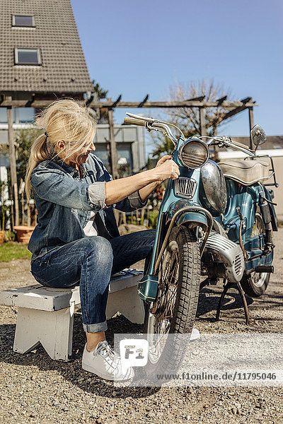 Frau reinigt Oldtimer-Motorrad
