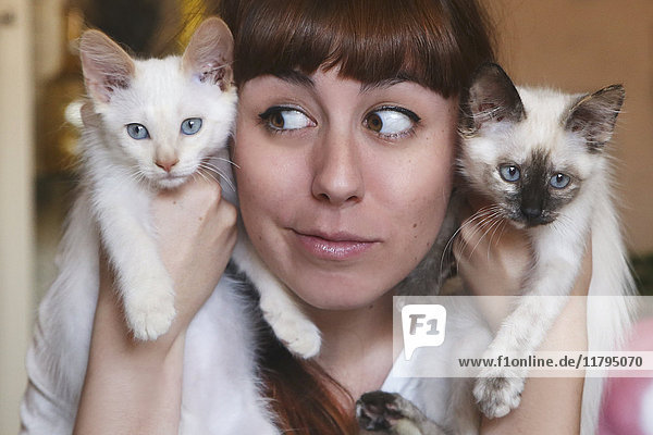 Lustiges Porträt einer jungen Frau mit zwei Kätzchen
