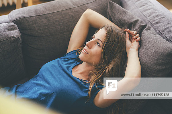 Entspannte junge Frau auf der Couch zu Hause liegend