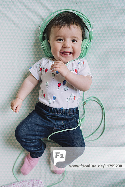 Portrait des glücklichen Mädchens mit Kopfhörer auf der Decke liegend