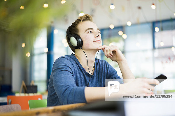 Porträt eines jungen Mannes beim Musikhören mit Kopfhörern im Café