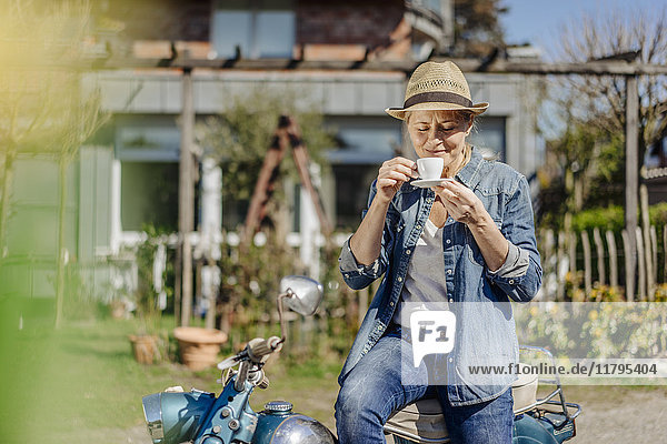 Woman on vintage motorcycle enjoying a coffee break